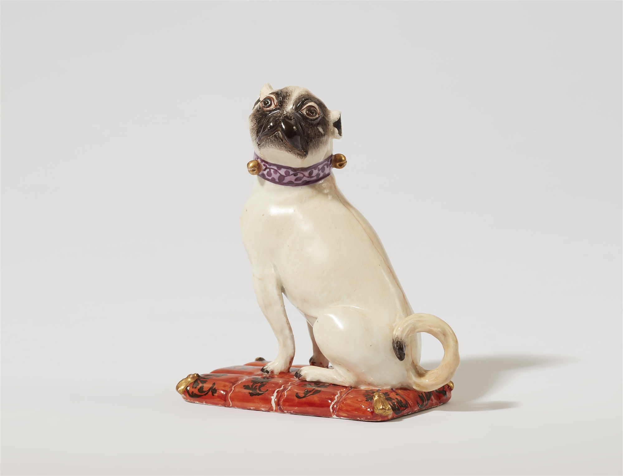 A Meissen porcelain model of a pug dog on a cushion