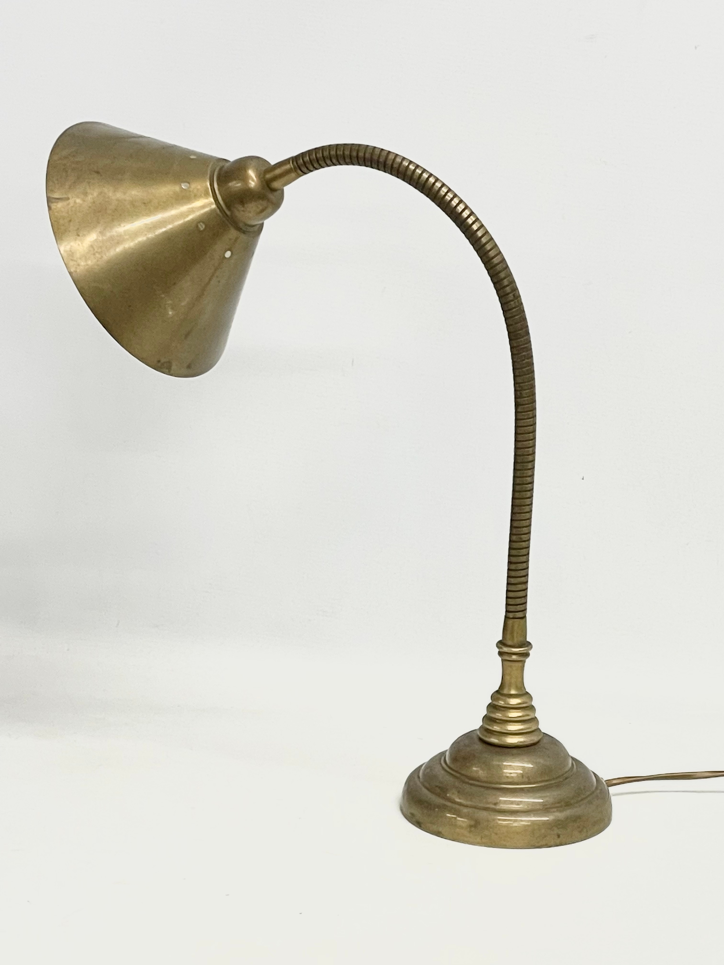 A large brass swan neck desk lamp.