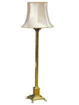 A vintage brass standard lamp with Corinthian style column on lion paw feet. 167cm