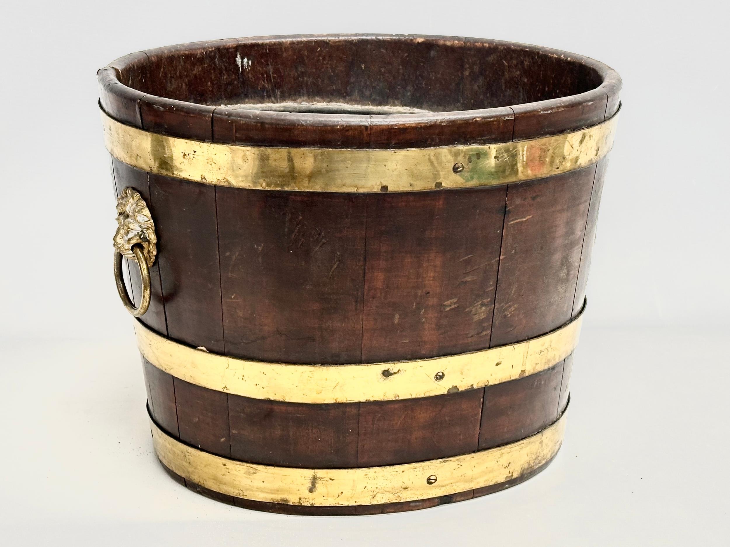 A George III brass bound wine cooler with lion ring handles and original liner. Circa 1780-1790.