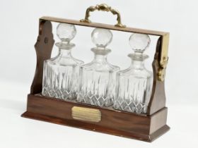 A mahogany and brass tantalus with 3 matching crystal decanters. No key. 39x15x35cm