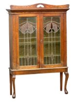 An early 20th century Art Nouveau oak bookcase on stand with stained glass panel doors. Circa 1910-