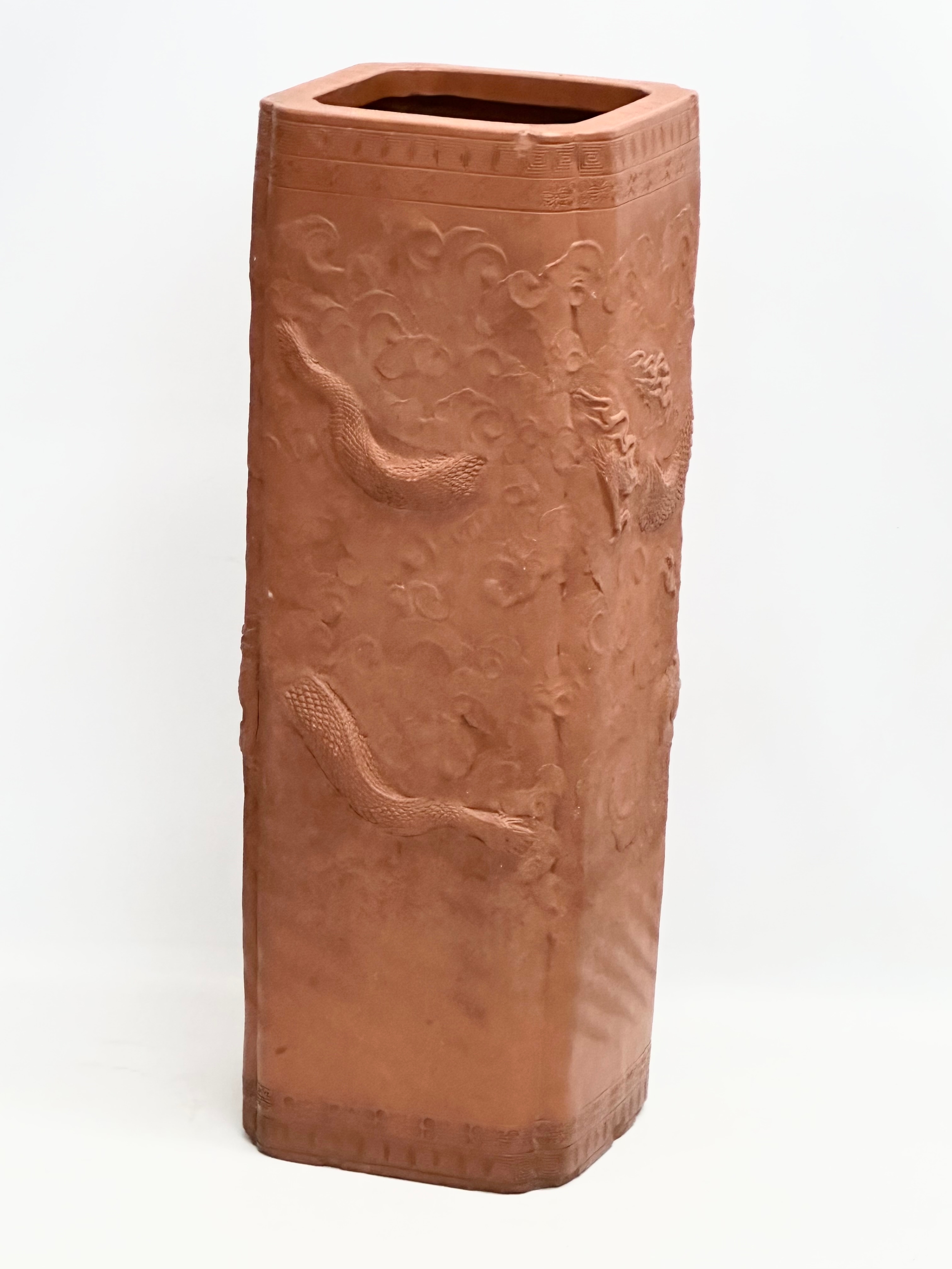 A Chinese terracotta stick stand/planter with dragon motif and Greek Key decoration. 21x21x61cm