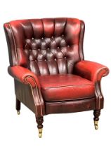 A Victorian style deep buttoned ox blood leather armchair on brass cup casters. 85x75x93cm