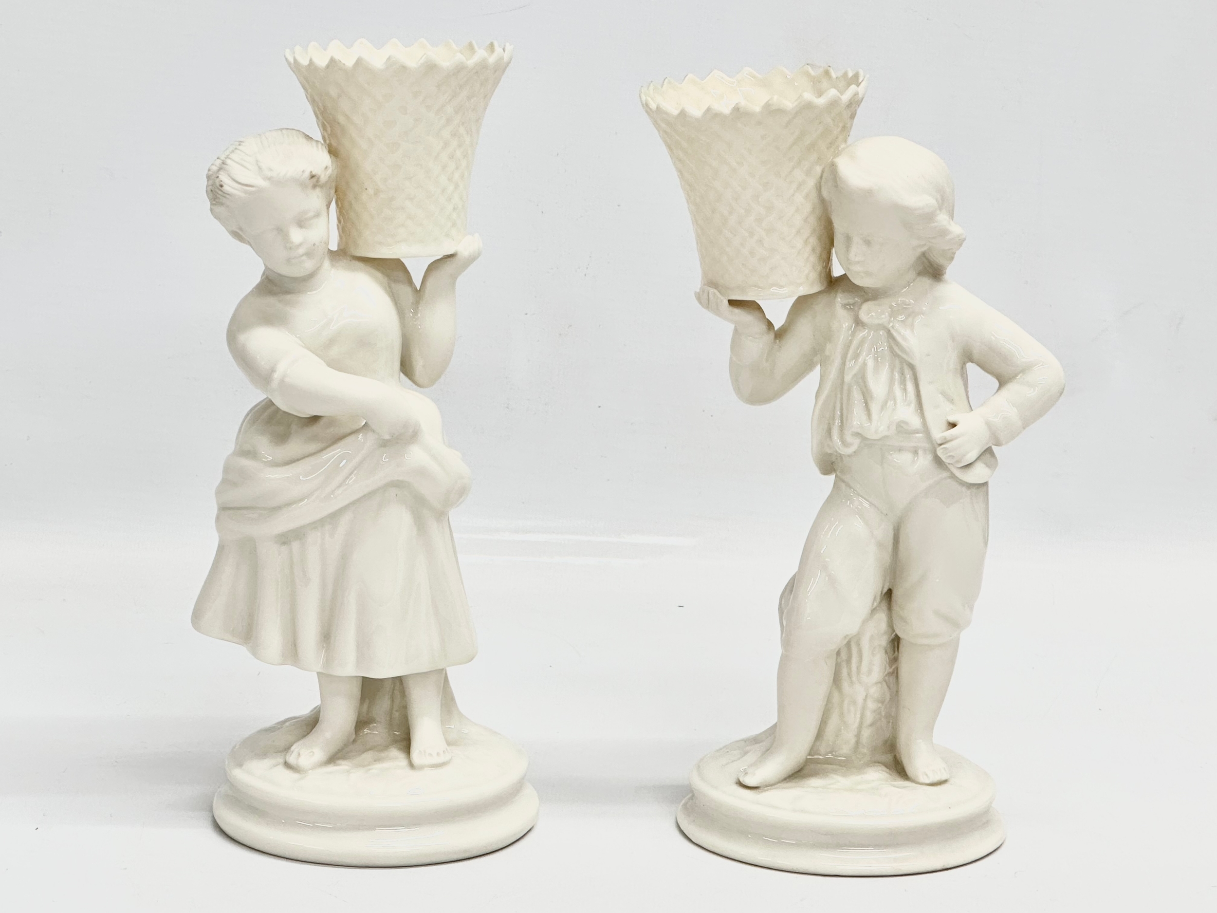 A pair of Belleek Pottery ‘Basket Carrier’ figurines. Girl basket Bearer, Boy Basket Bearer. 21.5cm