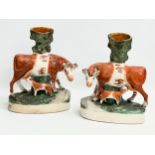 A pair of mid/late 19th century Staffordshire Cow spill vases. 22x27.5cm