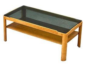 A Mid Century teak coffee table with smoked glass top by Myer. 88x44x35cm
