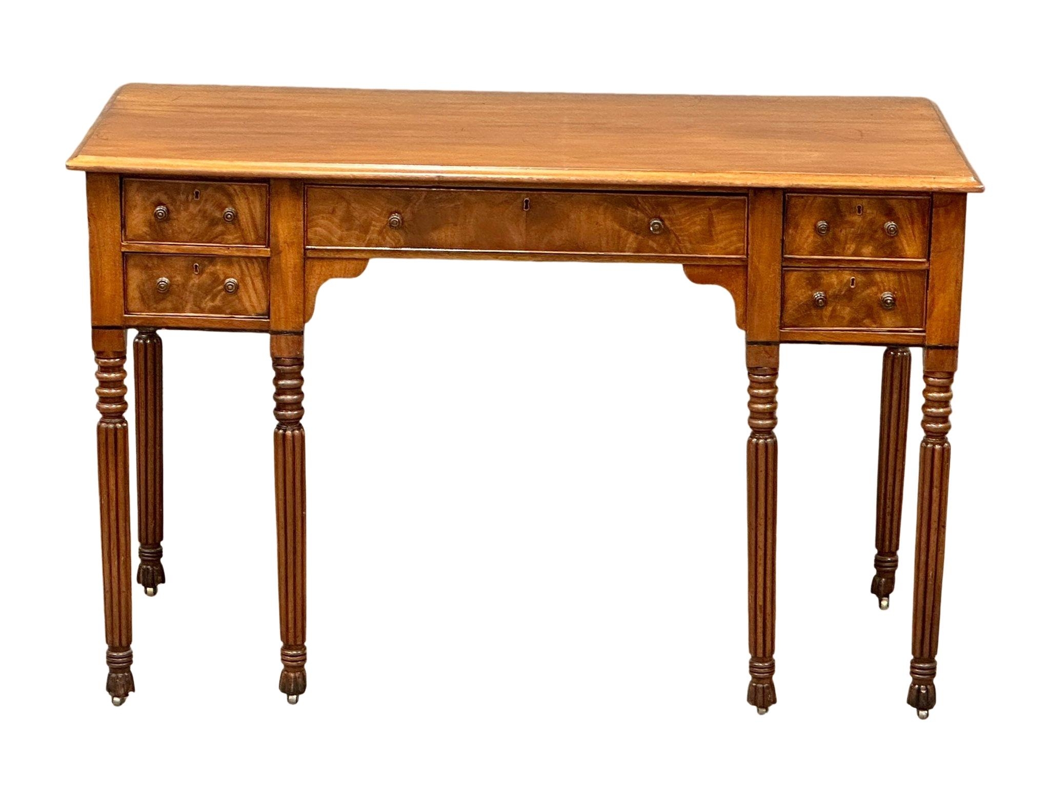 A late George IV mahogany side table/desk on reeded legs. 126cm x 61cm x 80cm