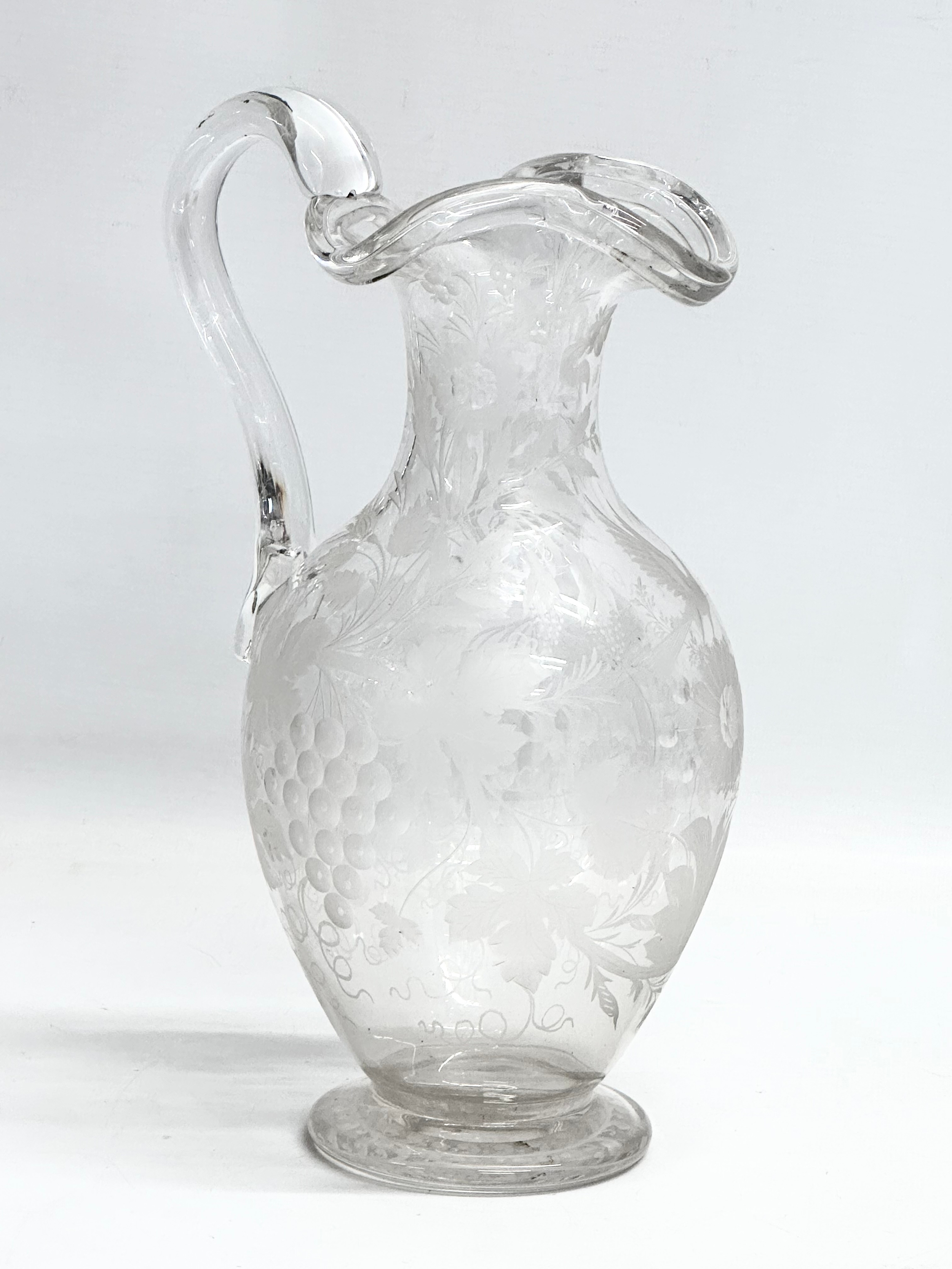 An etched glass pitcher in the manner of William Fritsche. Decorated with leaves, grape vines and