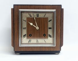 An Art Deco Walker & Hall walnut mantle clock on chromed feet. Circa 1930-1950. With pendulum.