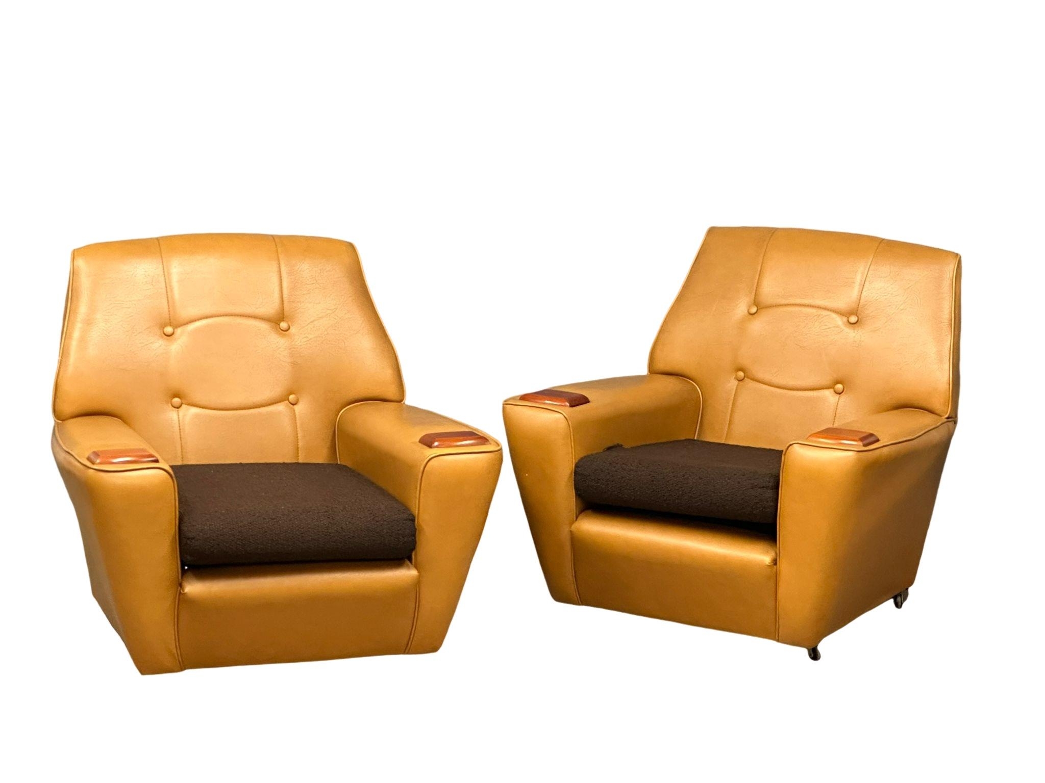 A pair of Mid Century faux leather armchairs with teak padded arms. 1970’s.