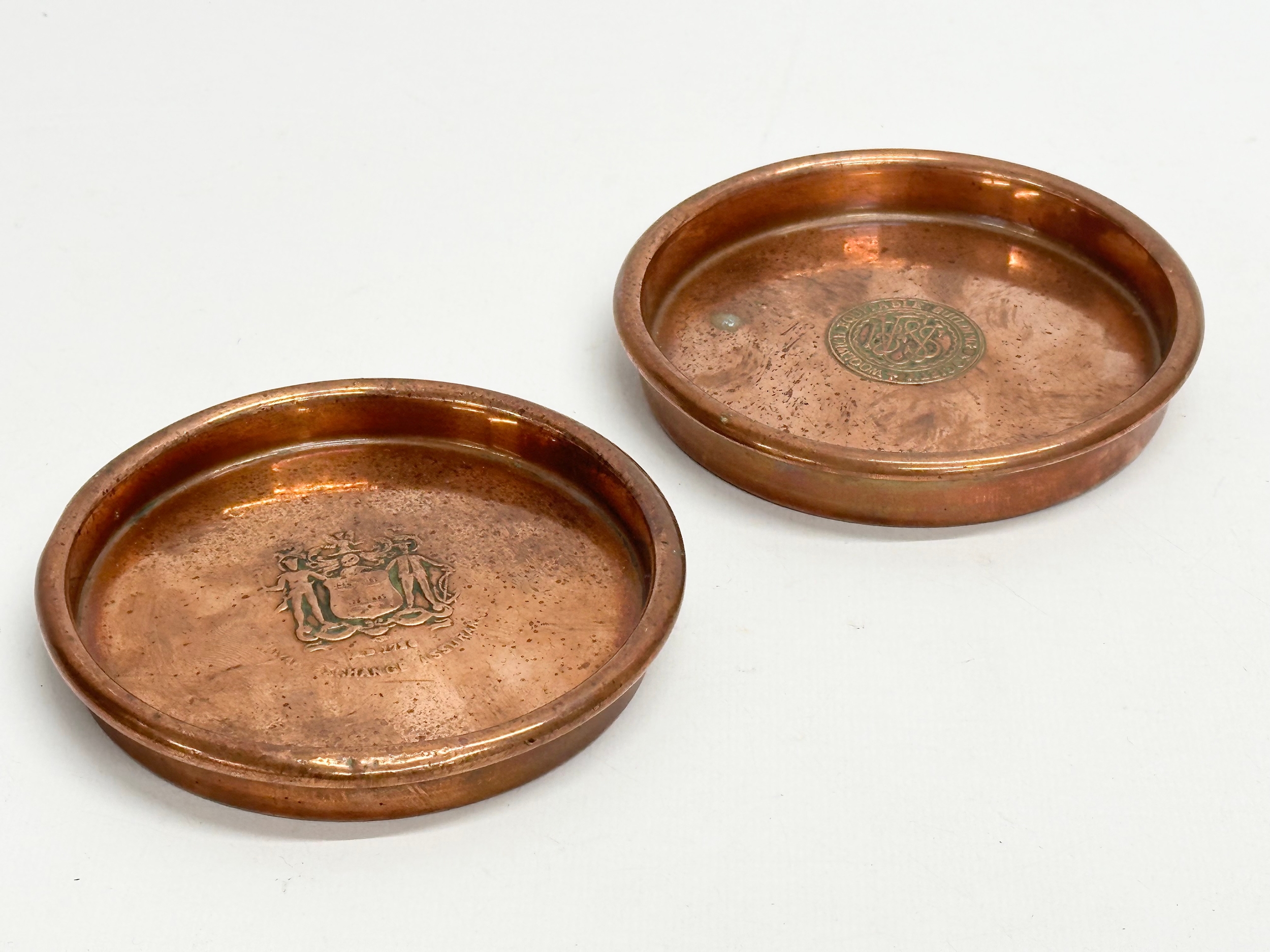 A pair of heavy copper wine coasters by Henry Jenkins & Sons LTD. Woolwich Equitable Building