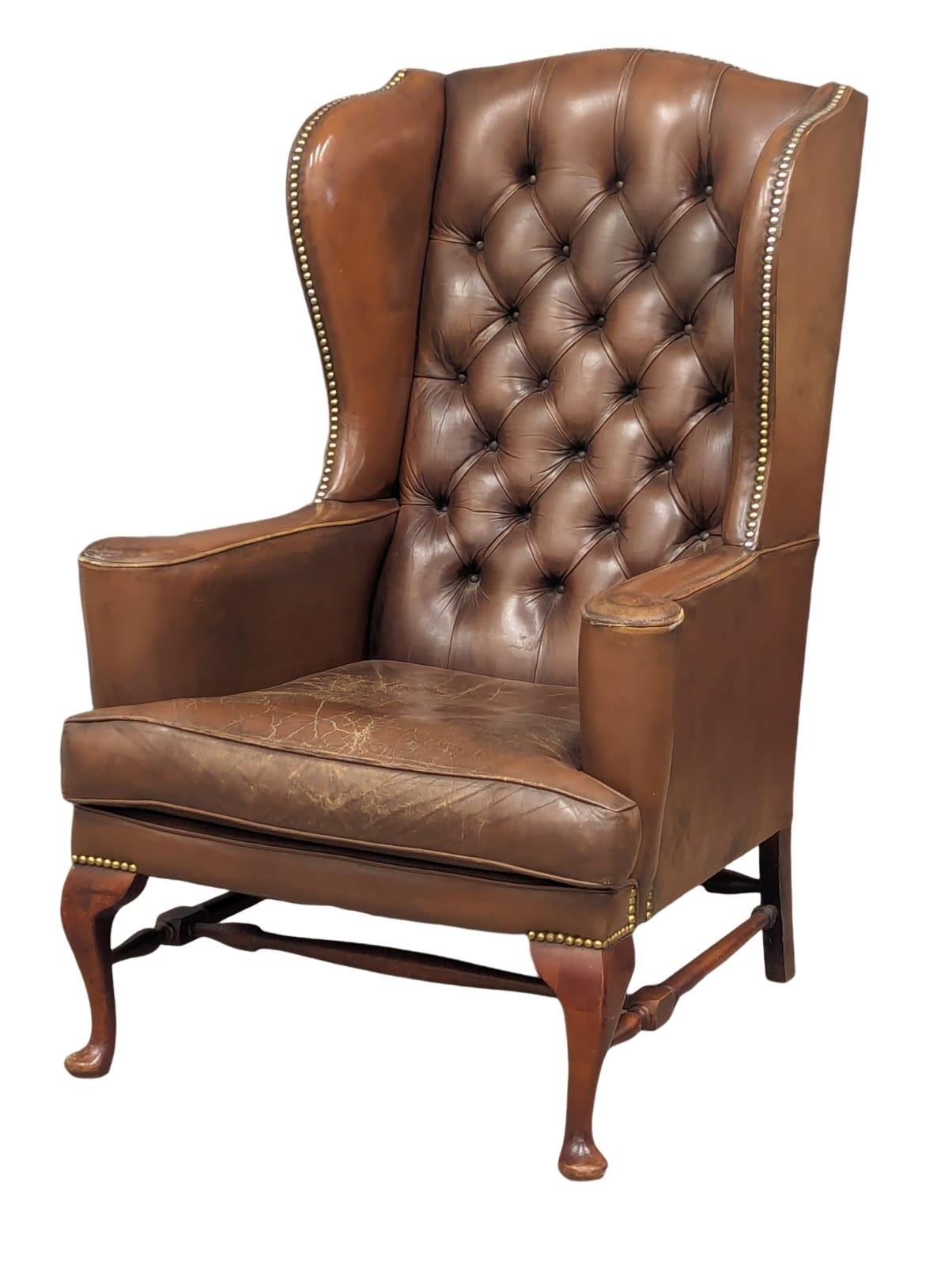 A brown deep button back leather wingback armchair in the early Georgian style