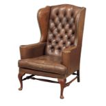 A brown deep button back leather wingback armchair in the early Georgian style
