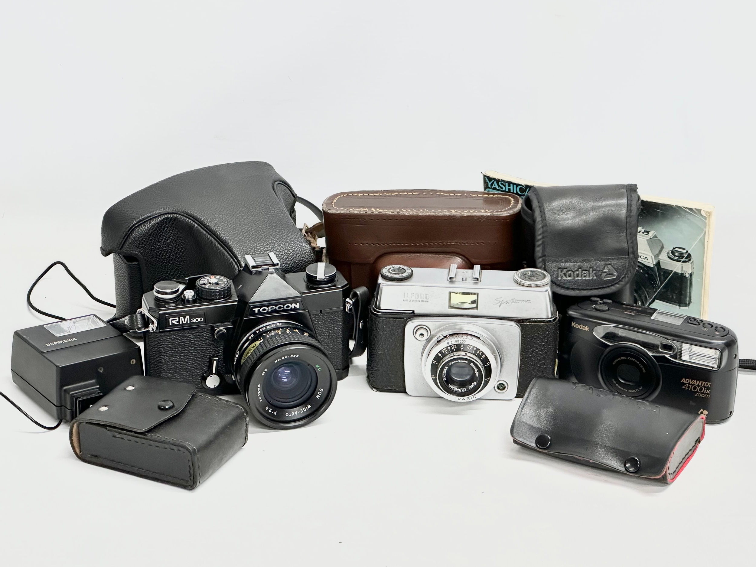 A collection of cameras. Topcon RM300 with case. Ilford Sportman camera with case. Kodak Advantix