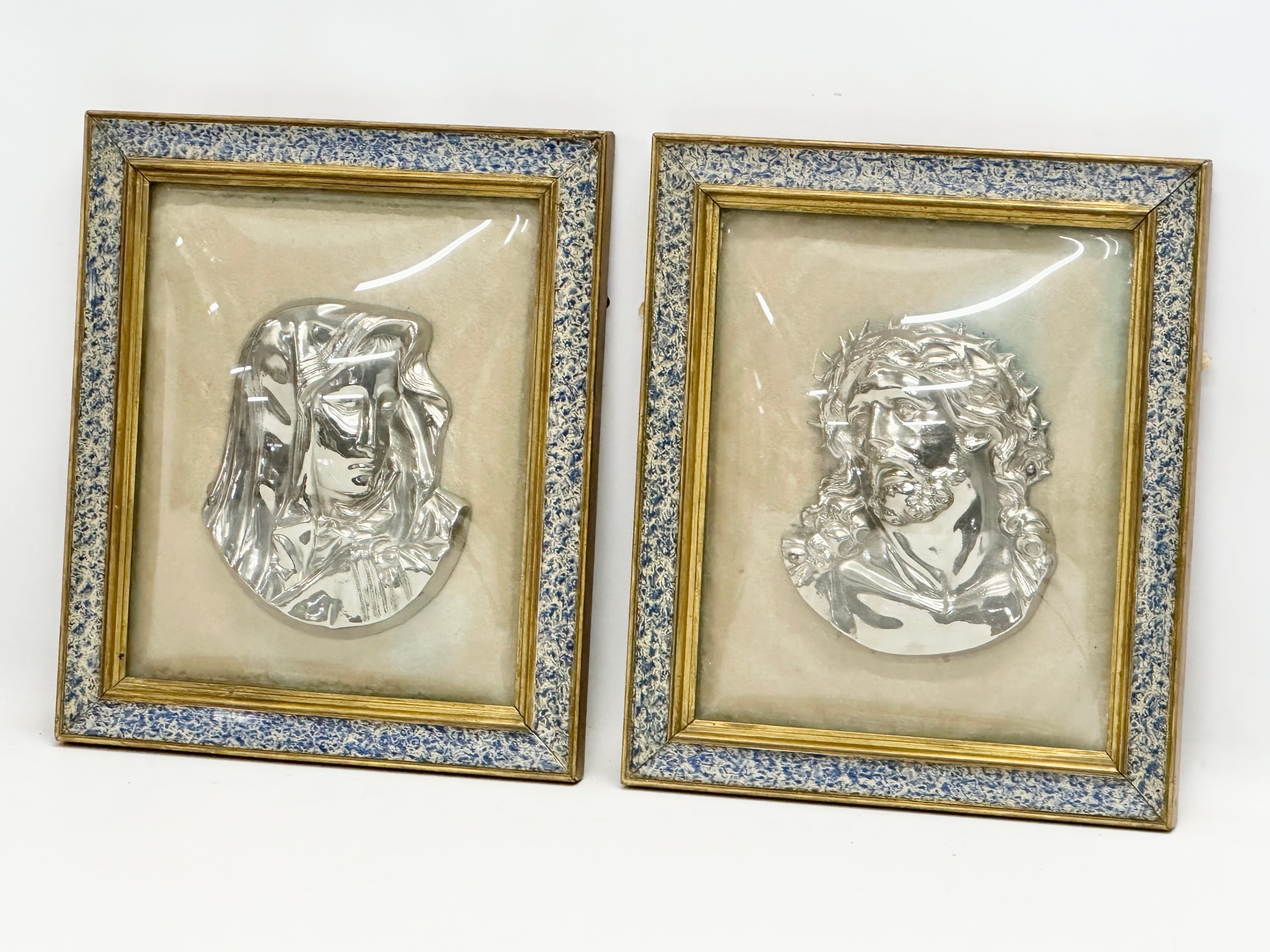 A pair of Early 20th Century plated religious wall plaques with convex glass and gilt frames.