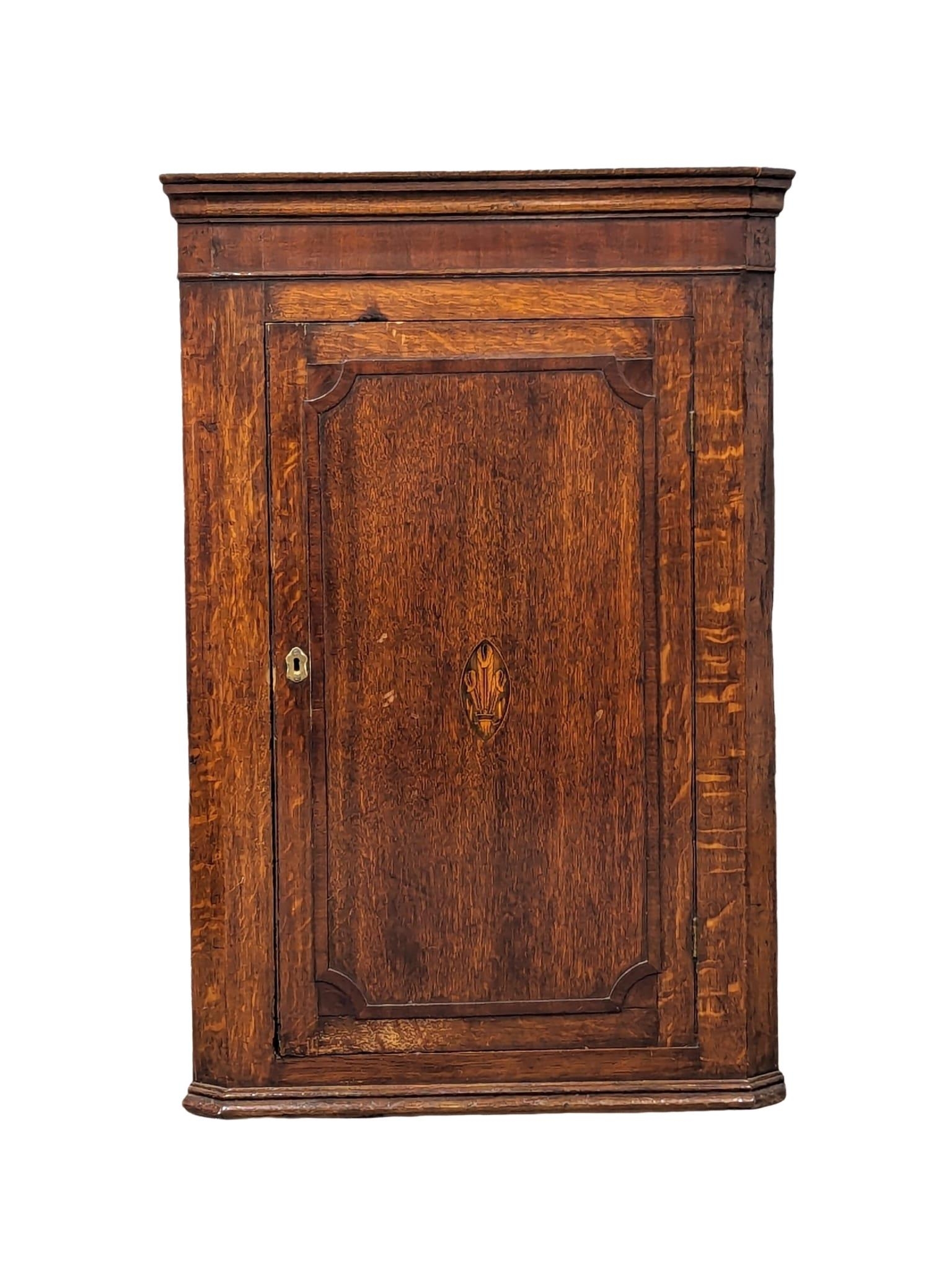 A George III inlaid oak wall hanging corner cabinet with fitted shelves. Circa 1790-1800. 69.5x38.