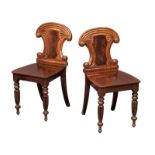 A pair of late George IV-Early William IV ornate mahogany hall chairs