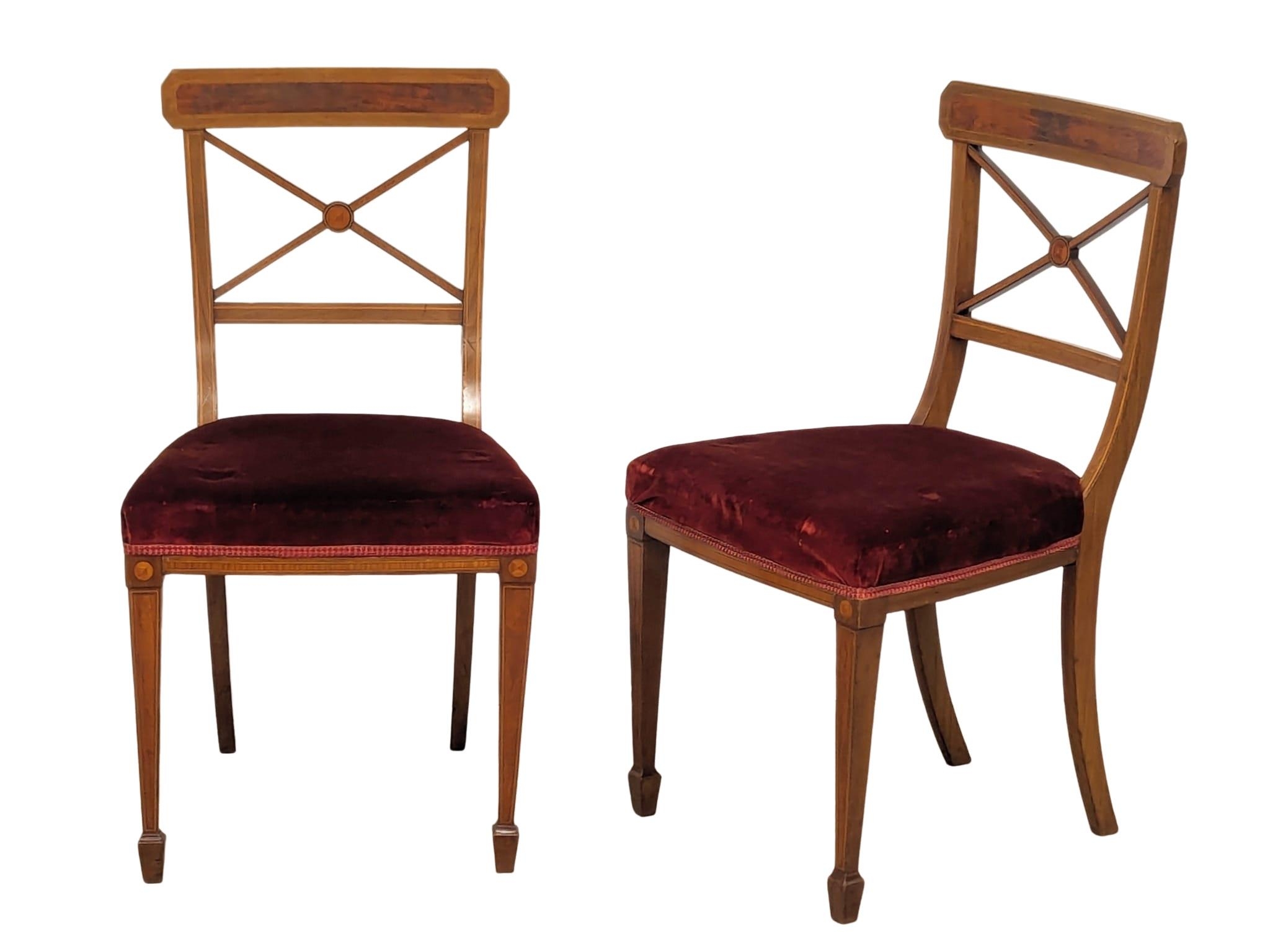 A pair of Edwardian inlaid mahogany side chairs on square tapering legs. In the Sheraton style.