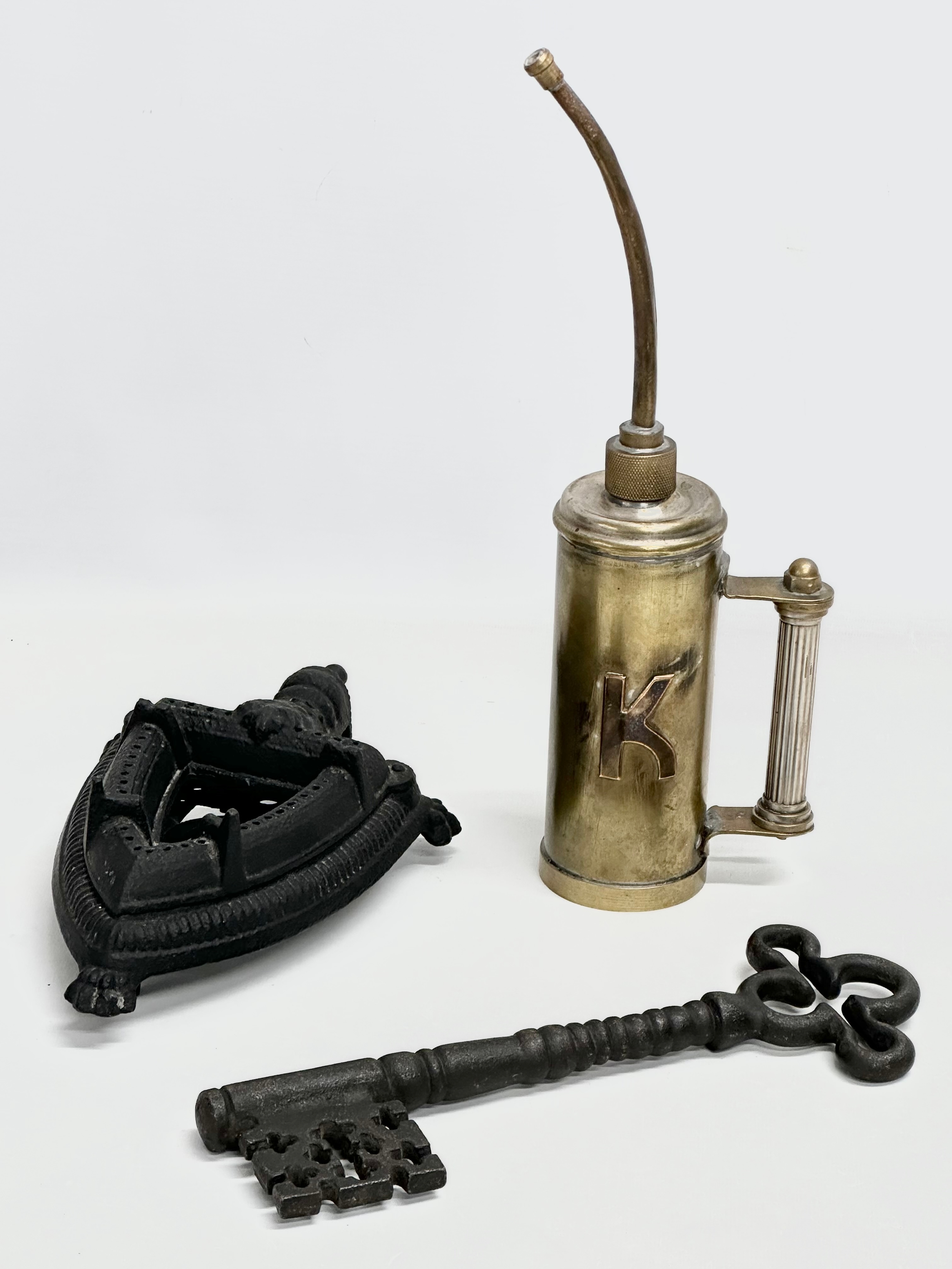 A job lot. An oil dispenser 34cm. A large ornamental key 28cm. An iron on trivet stand.