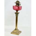 A large Victorian Ruby glass oil lamp with brass Corinthian style column. 60cm