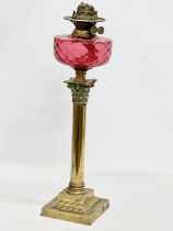 A large Victorian Ruby glass oil lamp with brass Corinthian style column. 60cm