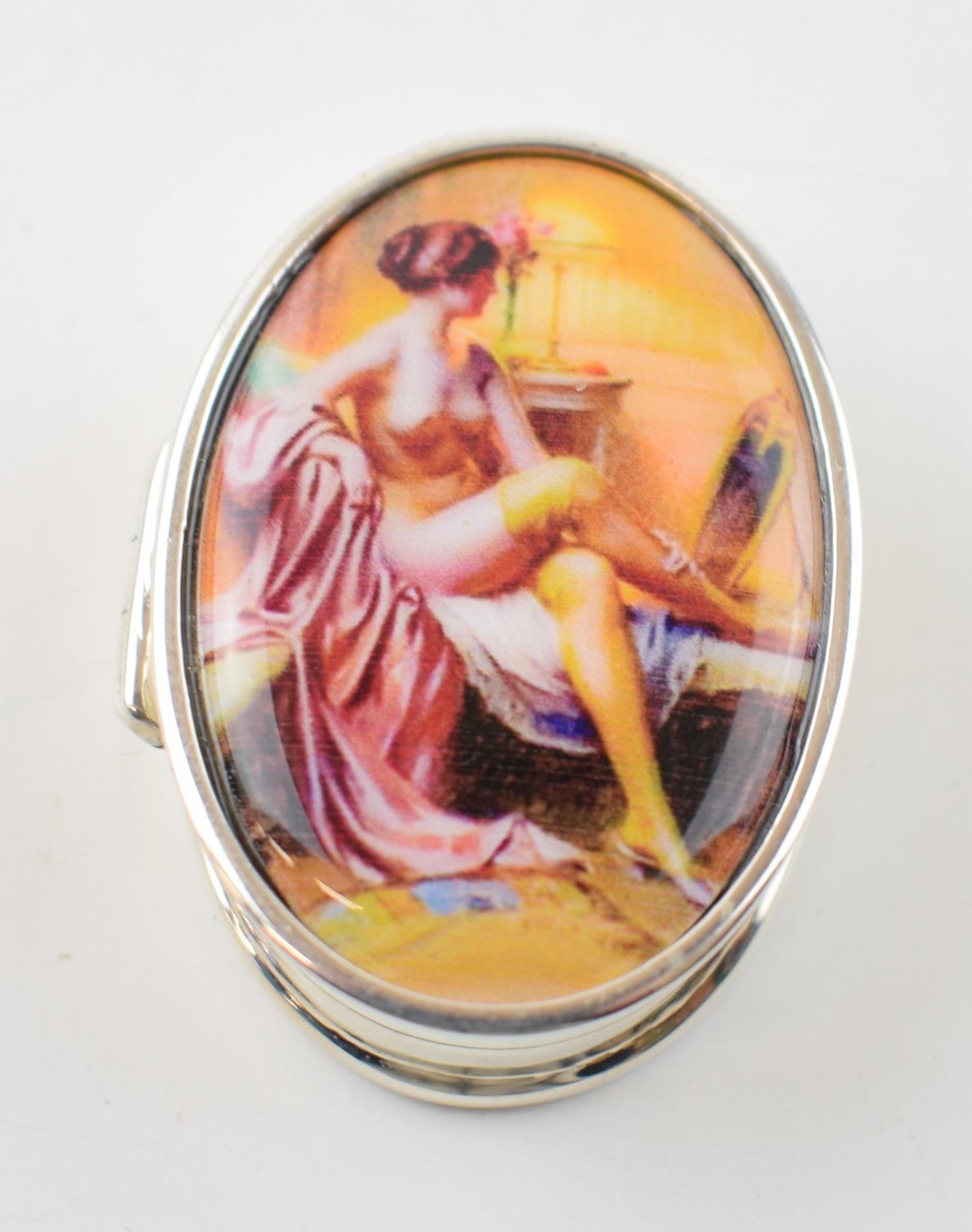 Sterling silver pill box with enamelled insert of a semi-erotic scene, 19.3 grams, 4cm long.