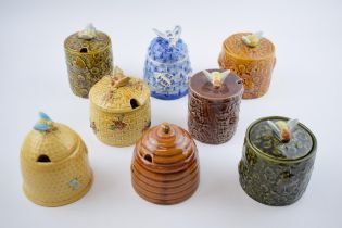 A collection of pottery honey pots in varying forms and colours to include Secla, Holkham, a Delft