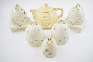 A collection of Belleek honey pots in varying forms and colours to include raised examples with a