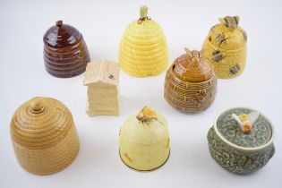A collection of pottery honey pots in varying forms and colours to include Mintons (wings re-stuck),