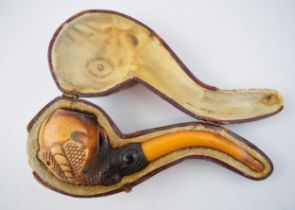 Cased early 20th century meerschaum smoking pipe in the form of a ball and claw with amber handle,