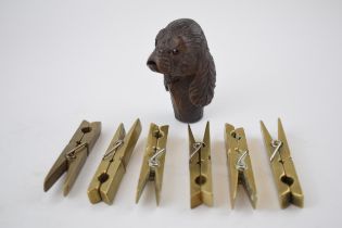 A collection of 6 brass clothes pegs, working order, with a carved wooden stick handle in the form