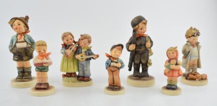 A collection of Goebel and Hummel child figures to include a girl with a doll, a boy with ladders, a