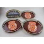 Four tin Newcastle Brown Ale advertising pub trays. Three of the same design with brown ground and