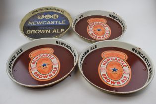 Four tin Newcastle Brown Ale advertising pub trays. Three of the same design with brown ground and