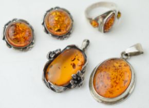 A collection of silver mounted amber jewellery to include a pendant, with another floral mounted