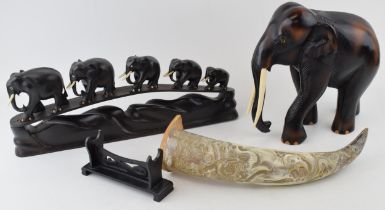 Carved elephant with bone tusks, a carved horn and a stand together with row of five elephants in