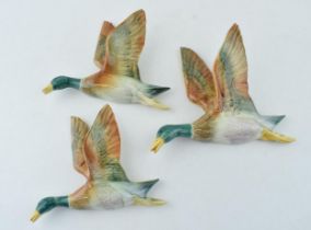 A trio of pottery wall plaques in the form of flying mallard ducks, unmarked, though in the manner