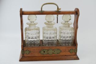 Tantalus in golden oak with brass fittings. Containing three glass decanters, with original key.