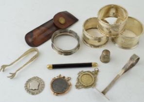 A collection of silver items to include napkin rings, thimble, fob and sugar nips (approx 90