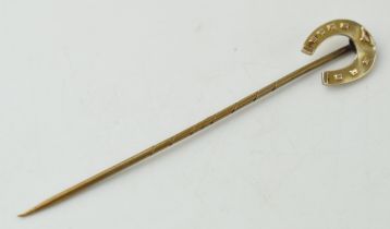 9ct gold stick pin in the form of a horse's shoe, on base metal pin, 1.3 grams, 72mm long.