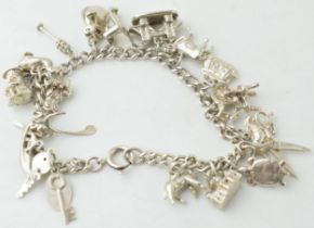 Silver charm bracelet with circa 19 charms to include scissors, a turtle, a toby jug and others,