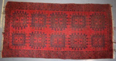 A hand-knotted oriental / middle-eastern carpet in deep reds, blue and blacks. 93cm x 190cm. In good