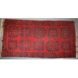 A hand-knotted oriental / middle-eastern carpet in deep reds, blue and blacks. 93cm x 190cm. In good