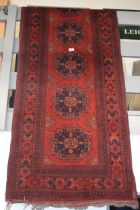 A oriental / middle-eastern runner carpet / rug in deep reds, blues, oranges and cream. 83cm x