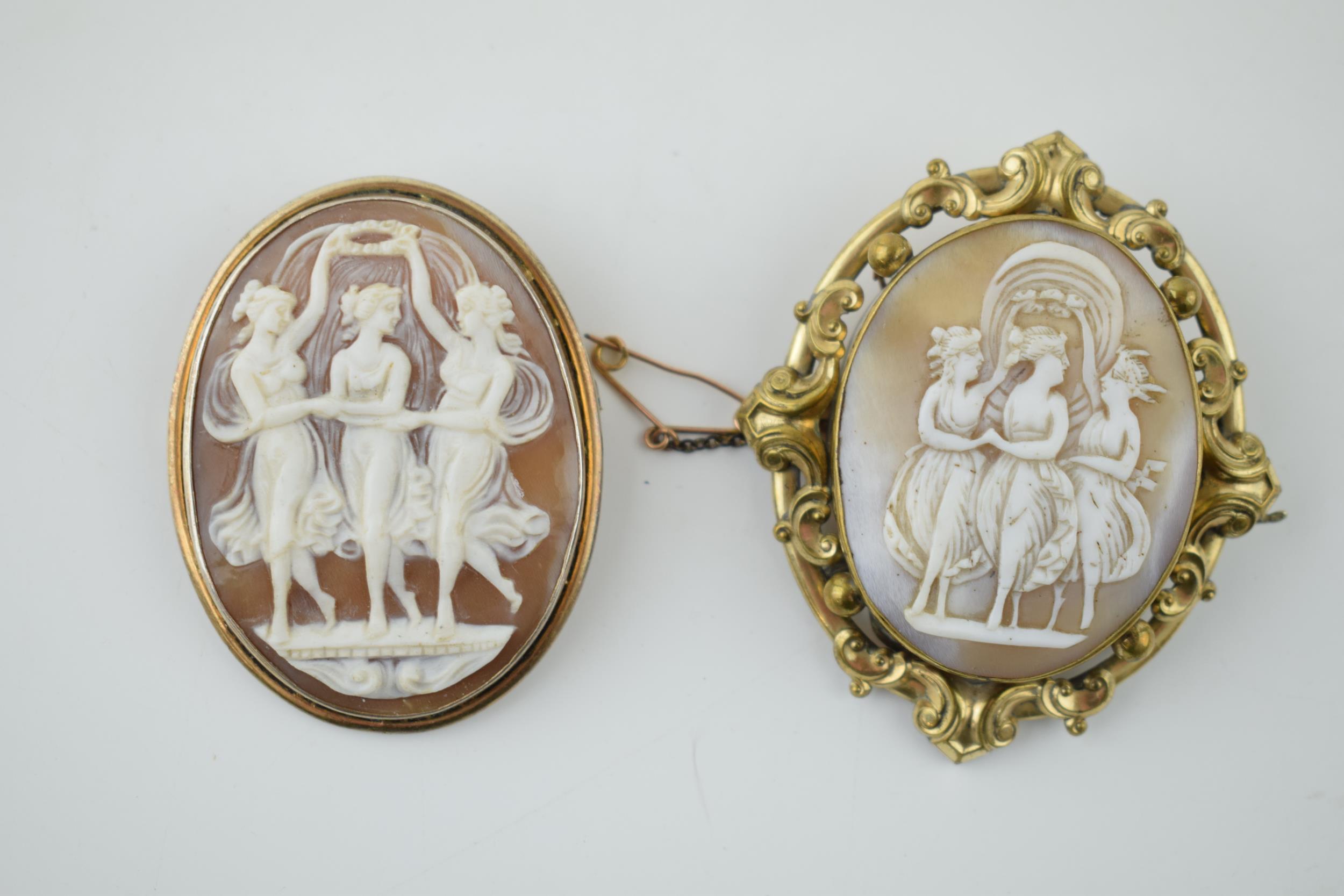 A pair of vintage cameo brooches, both depicting the three graces, metal frames (2), 6cm tall.