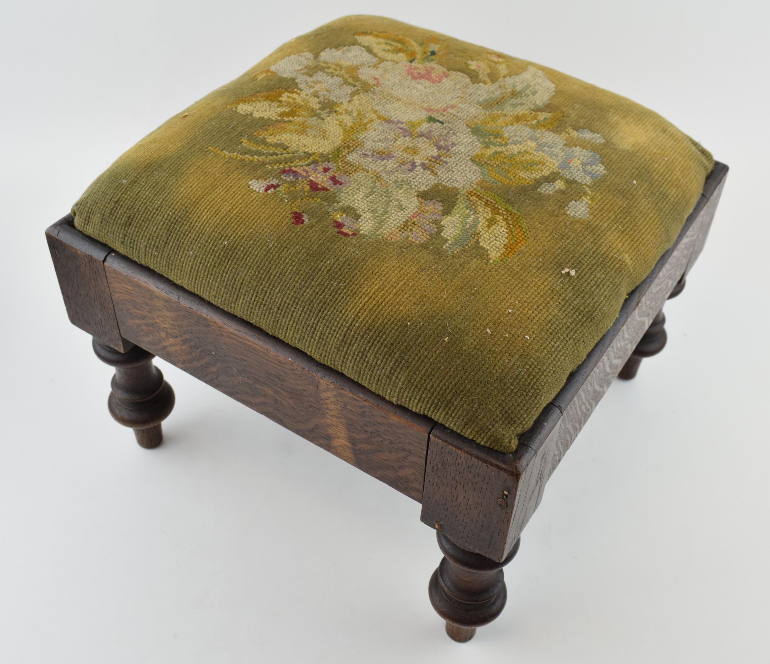 An antique footstool with tapestry decoration to top. Height 23cm.