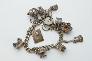Silver charm bracelet with a guitar, a carriage, a lamp and others, 64.2 grams.