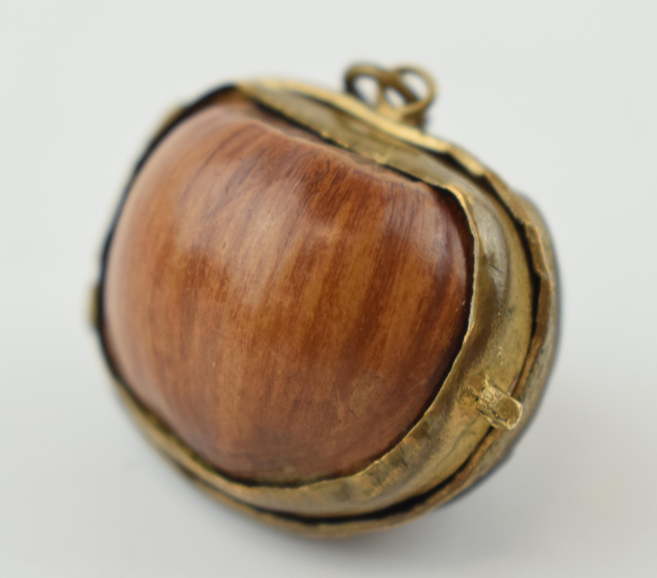 A miniature purse made form a hazelnut shell with brass hinge and mount. 2.5cm.