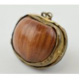 A miniature purse made form a hazelnut shell with brass hinge and mount. 2.5cm.